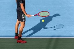 Tennis player bouncing ball near base line on blue hard court befor service, starting match. Sports
