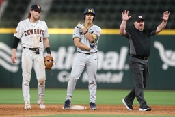 February 23, 2024, Arlington, Texas, USA: Second base unpire JOHN BRAMMER calls for a stoppage in play to allow Michigan